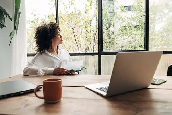 Junge Frau sitzt an einem Arbeitsplatz am Fenster